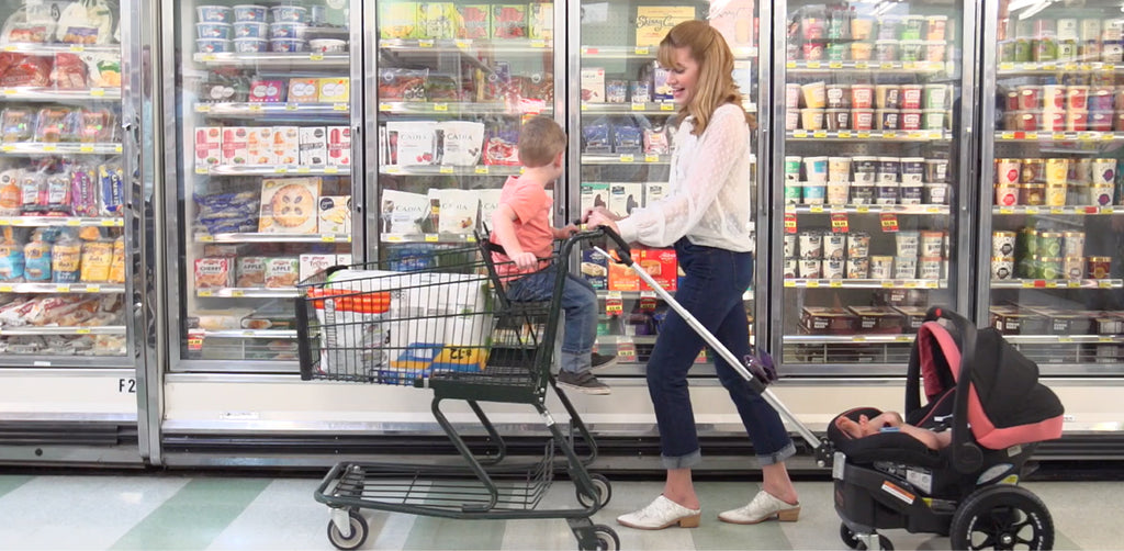 mother pushing child in shopping cart while pulling infant in Dash Wagon